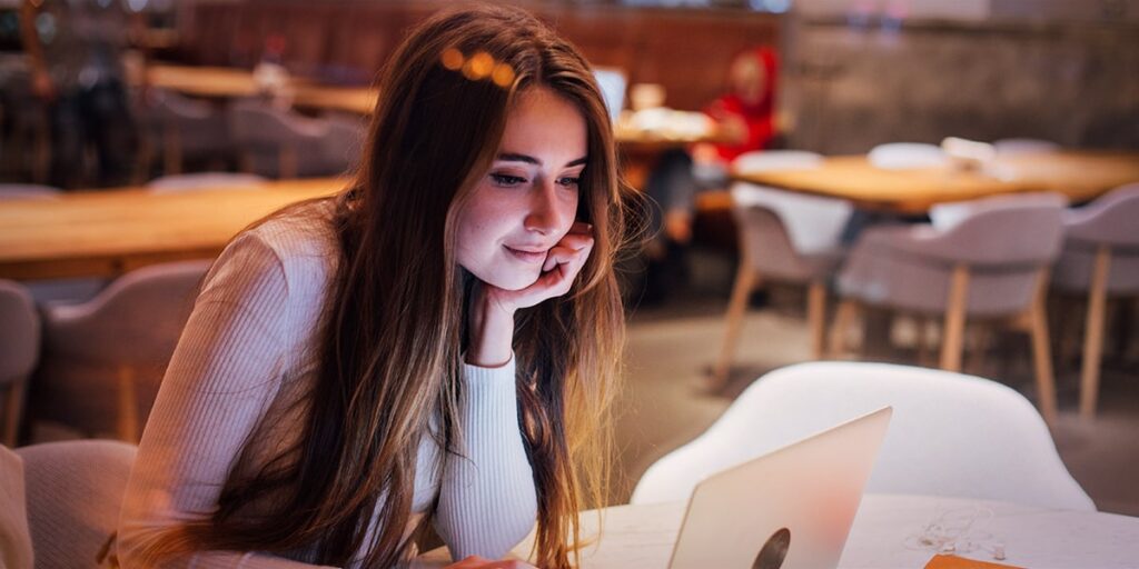 mulher ao notebook em café estudando marketing de conteúdo