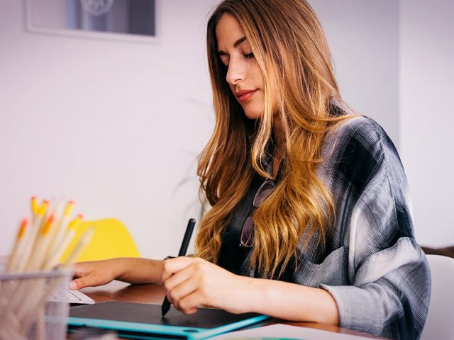 mulher designer usando mesa digitalizadora para fazer identidade visual para publicidade e propaganda de empresa