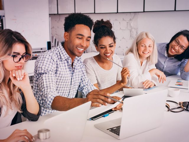 equipe em uma mesa sorrindo e trabalhando em agência de publicidade