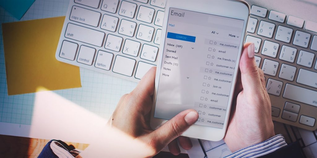 mãos ao celular verificando caixa de entrada com e-mail marketing