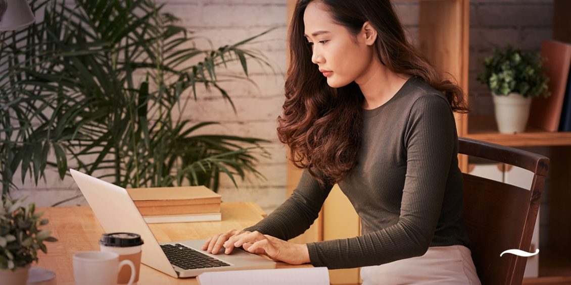 mulher sentada em escritório usando notebook para fazer e-mail marketing