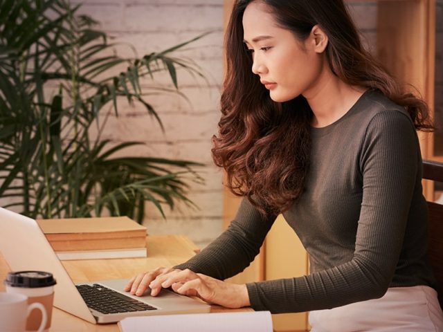 mulher sentada em escritório usando notebook para fazer e-mail marketing