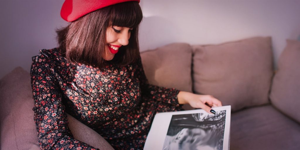 mulher de boina folheando revista olha anúncios publicitários