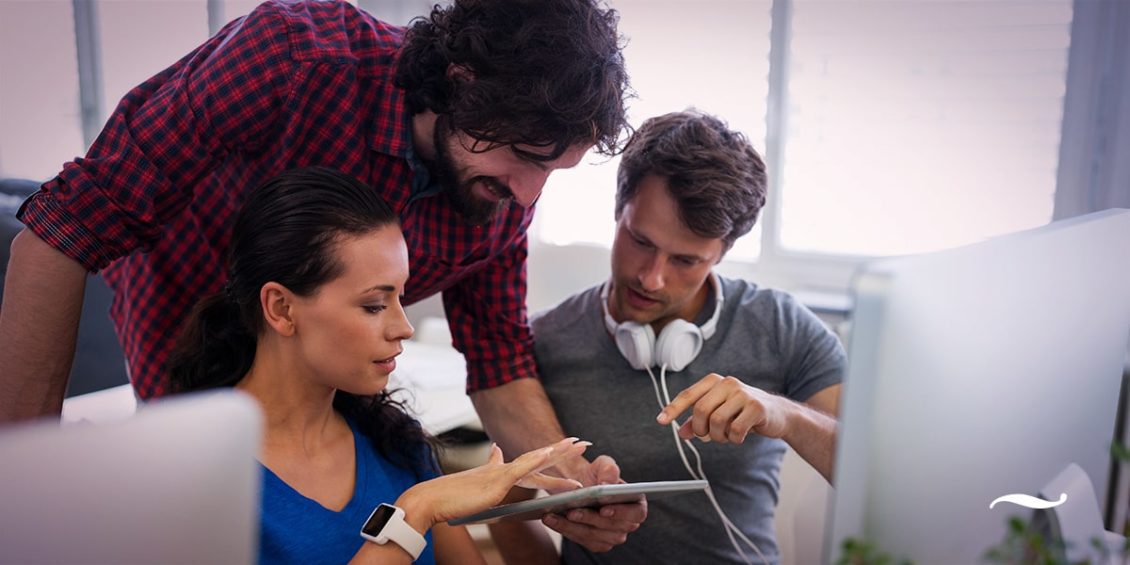 trio em agência vendo tablet e opinando sobre landing page para marketing digital