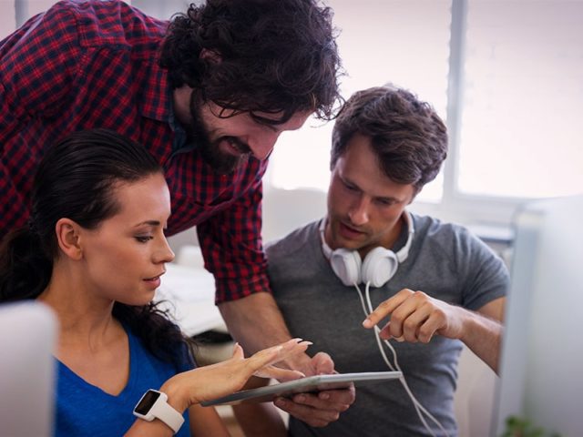 trio em agência vendo tablet e opinando sobre landing page para marketing digital