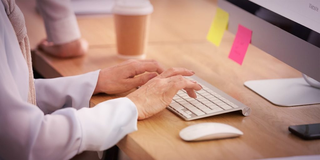 mulher ao computador planejando calendário editorial para redes sociais