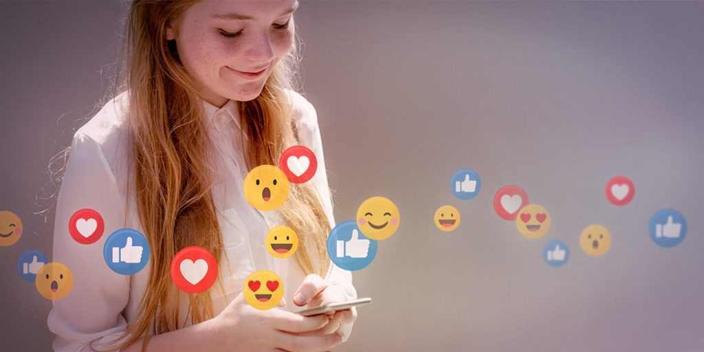 menina com celular cercada de emojis de mídias sociais