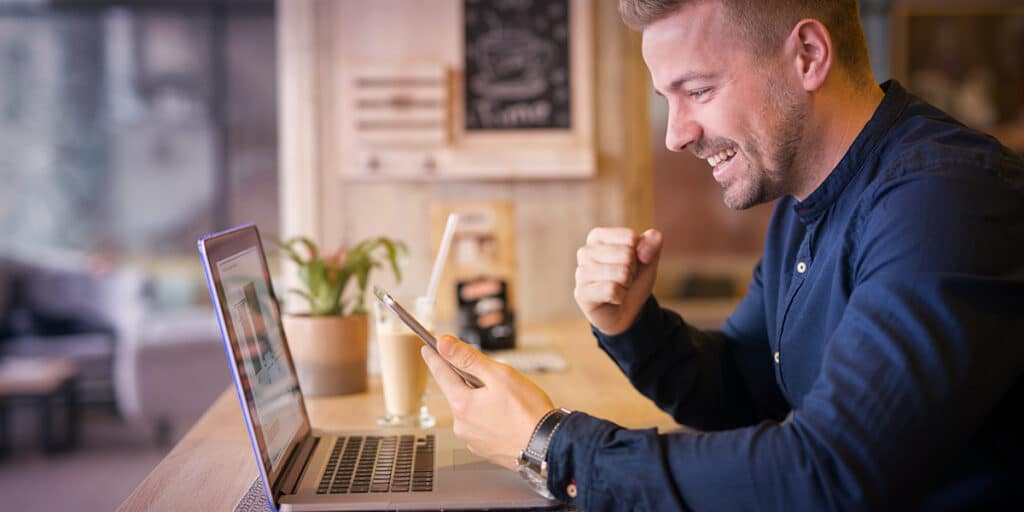 Homem olhando para seu site, comemorando bons resultados - site Tango Comunicação